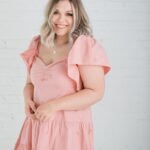 A woman in pink dress smiling for the camera.