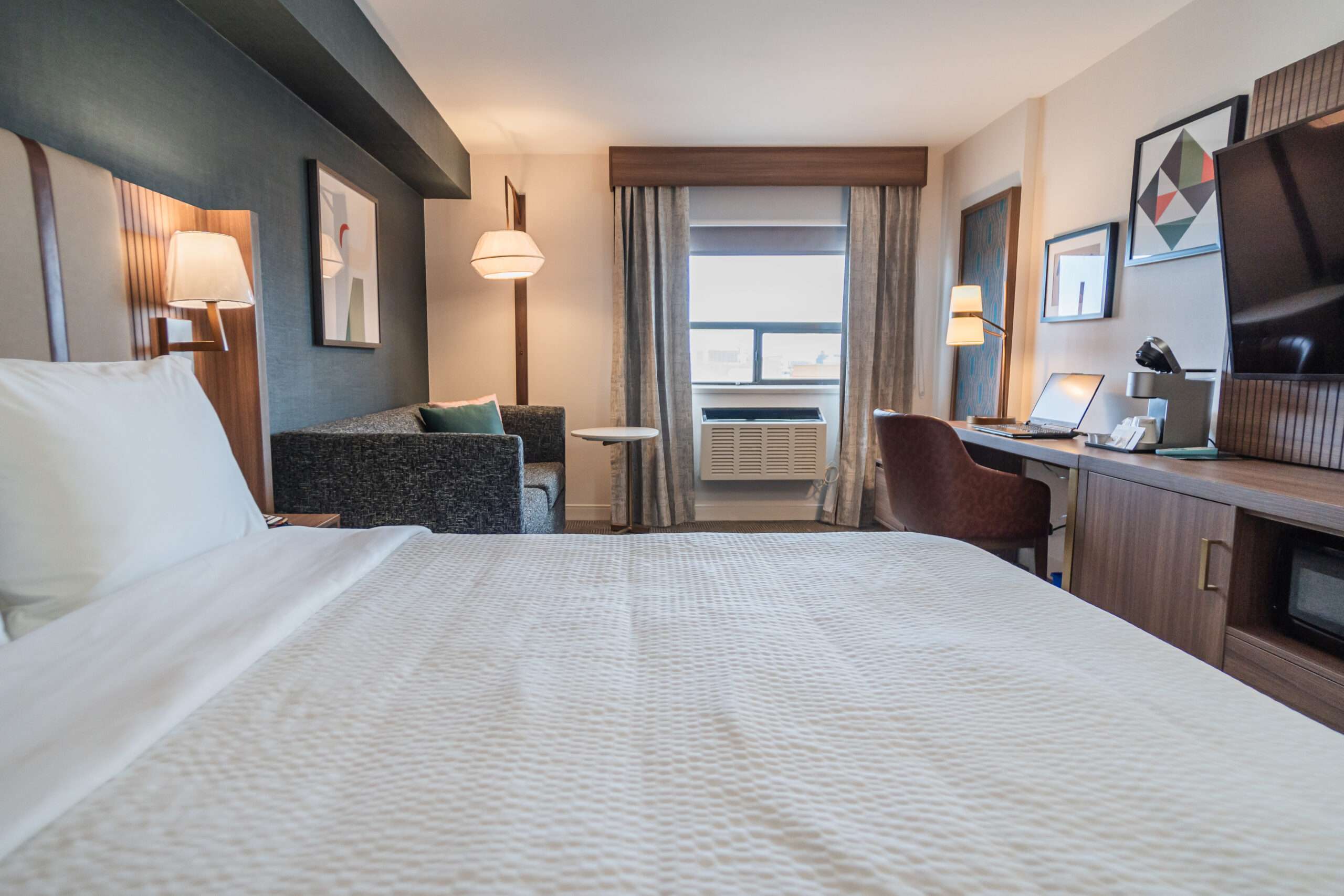 A hotel room with a bed, desk and chair. Canadian hotel room