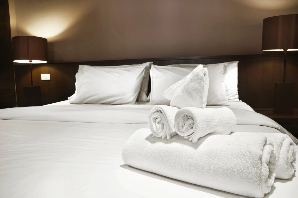 A bed with white sheet and two lamps on side